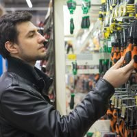 portrait of male customer choosing screwdrivers or turn-screws at supermarket store